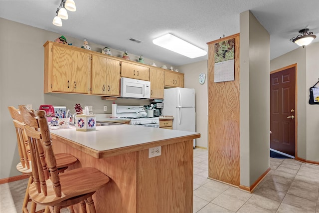 kitchen with a textured ceiling, white appliances, kitchen peninsula, and light brown cabinetry