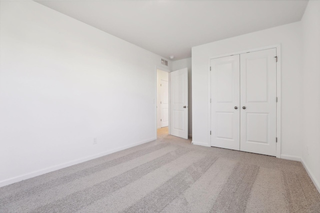 unfurnished bedroom with light carpet and a closet