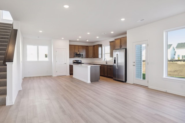 kitchen featuring a wealth of natural light, a center island, light wood-type flooring, and appliances with stainless steel finishes