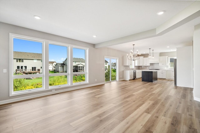 unfurnished living room featuring light wood-type flooring and an inviting chandelier