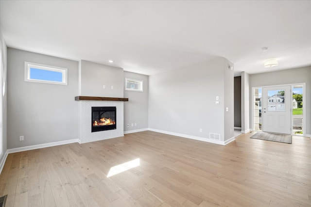 unfurnished living room with a tile fireplace and light hardwood / wood-style floors