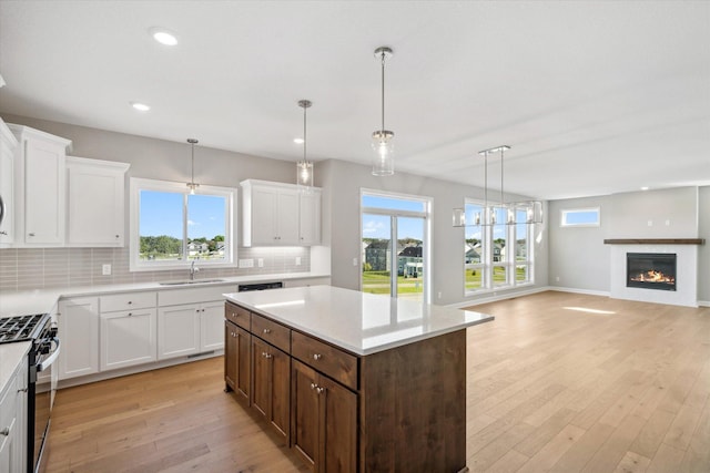 kitchen featuring light wood-type flooring, high end stainless steel range oven, sink, decorative light fixtures, and a center island