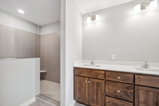 bathroom with tile patterned floors, vanity, and a tile shower