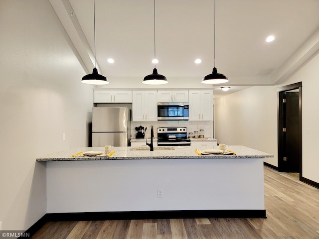 kitchen with white cabinets, stainless steel appliances, light stone counters, and tasteful backsplash