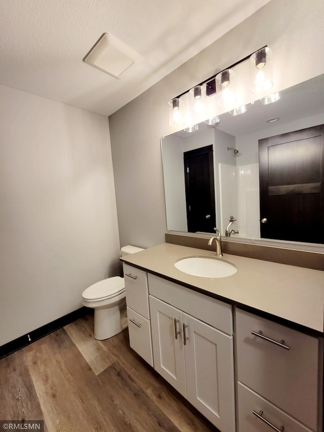 bathroom featuring vanity, a textured ceiling, a shower, wood-type flooring, and toilet