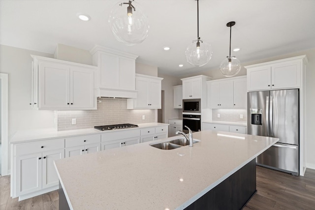 kitchen with appliances with stainless steel finishes, dark hardwood / wood-style flooring, sink, pendant lighting, and a center island with sink