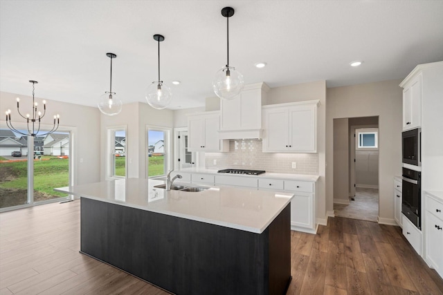 kitchen with a kitchen island with sink, pendant lighting, white cabinets, and stainless steel appliances