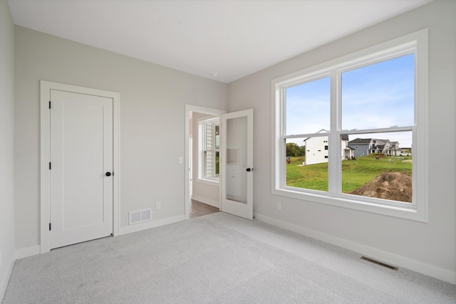 unfurnished bedroom featuring light carpet and french doors