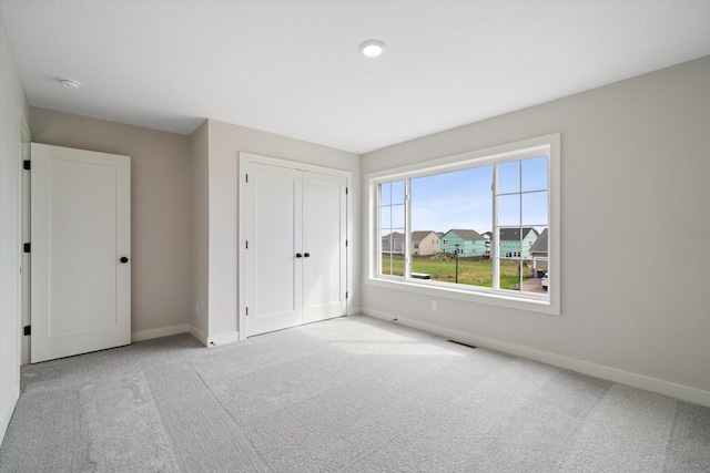 unfurnished bedroom with light carpet and a closet