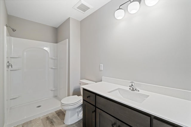 bathroom with a shower, hardwood / wood-style floors, vanity, and toilet