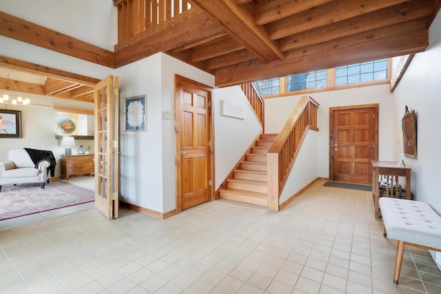 entryway with light tile patterned floors, baseboards, stairs, a towering ceiling, and beamed ceiling