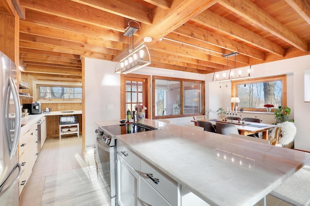 kitchen with light countertops, beam ceiling, light tile patterned floors, white cabinets, and stainless steel appliances