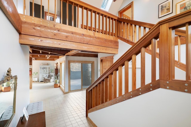 stairway featuring tile patterned floors, beamed ceiling, and a high ceiling