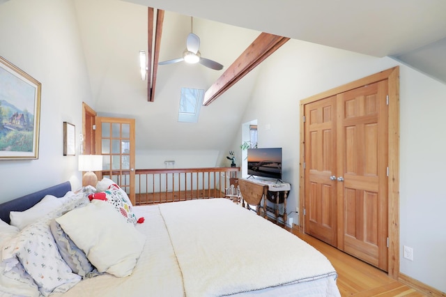 bedroom with vaulted ceiling with skylight, light wood-style floors, and ceiling fan