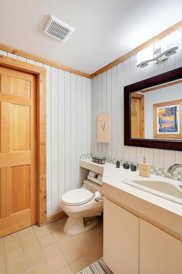 half bath featuring visible vents, toilet, vanity, and tile patterned flooring