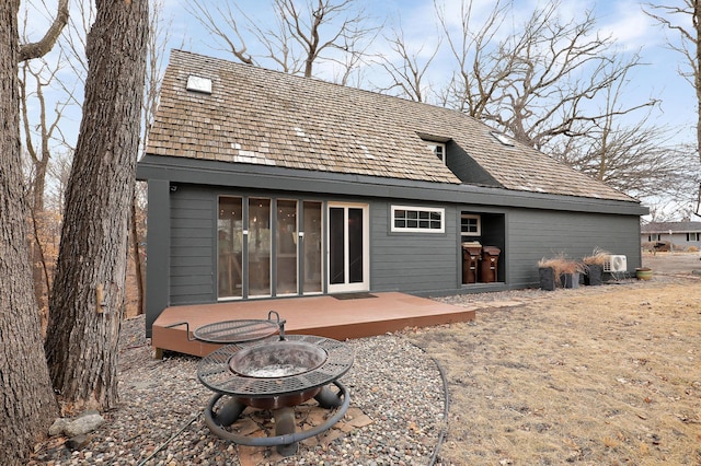 rear view of house with a wooden deck and an outdoor fire pit