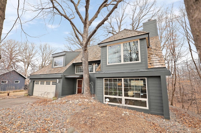 view of front of home featuring an attached garage, driveway, and a chimney