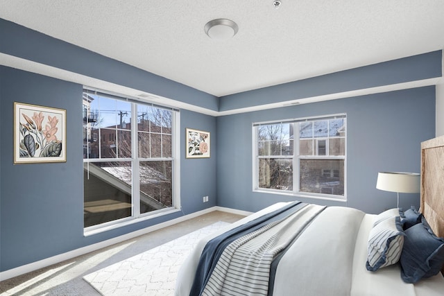 carpeted bedroom with baseboards, a textured ceiling, and multiple windows