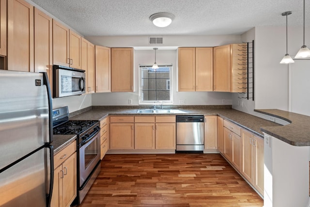 kitchen featuring light brown cabinetry, appliances with stainless steel finishes, and visible vents