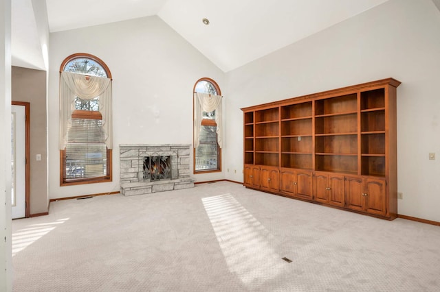 unfurnished living room with light carpet, high vaulted ceiling, and a stone fireplace