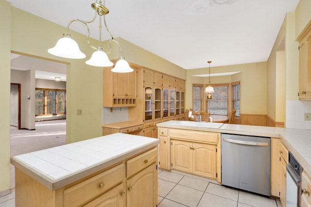 kitchen with tile counters, dishwasher, a center island, hanging light fixtures, and kitchen peninsula