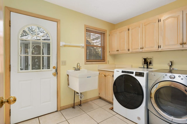 clothes washing area featuring washer and dryer, sink, light tile patterned floors, and cabinets