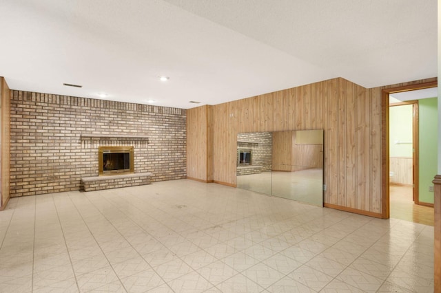 unfurnished living room featuring wooden walls, a fireplace, and brick wall