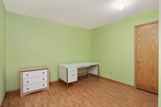 unfurnished office featuring a textured ceiling and light hardwood / wood-style floors