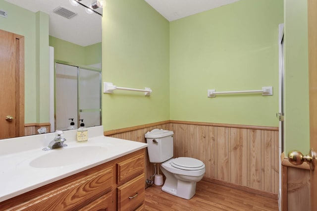 bathroom featuring vanity, a textured ceiling, wood-type flooring, toilet, and a shower with shower door