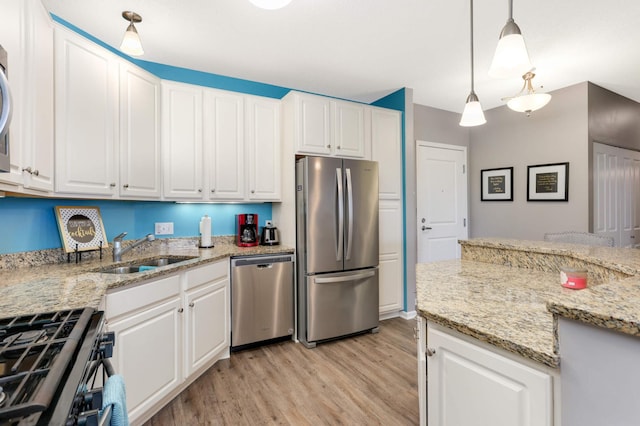 kitchen featuring pendant lighting, white cabinets, sink, light stone counters, and stainless steel appliances