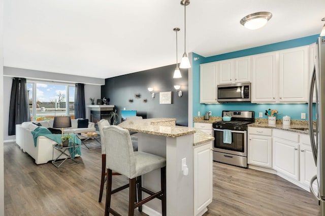 kitchen featuring white cabinets, appliances with stainless steel finishes, a center island, and light stone countertops