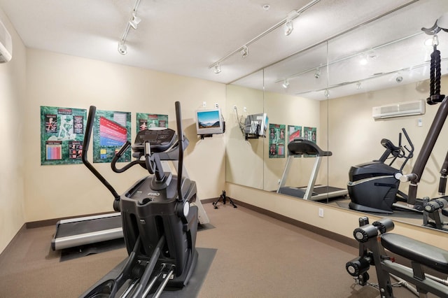 exercise room featuring a wall mounted air conditioner, carpet flooring, and rail lighting