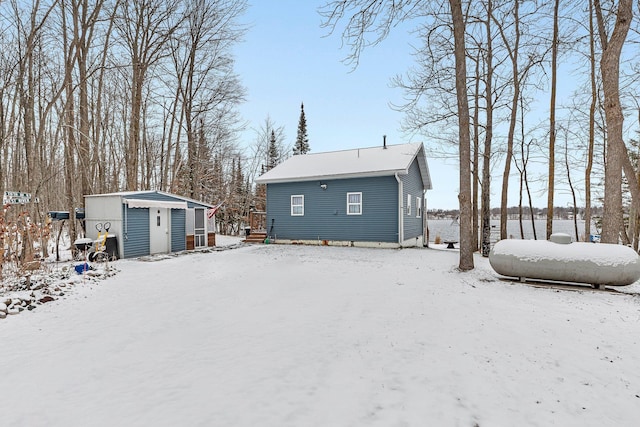 snow covered back of property with a shed