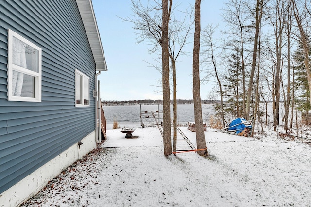 snowy yard featuring a water view and an outdoor fire pit