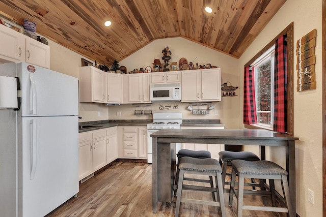 kitchen featuring a kitchen breakfast bar, white appliances, wooden ceiling, white cabinets, and hardwood / wood-style floors