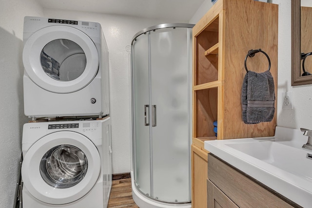 clothes washing area with dark hardwood / wood-style flooring, stacked washer and dryer, and sink