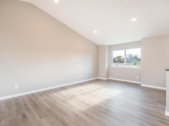 spare room featuring light hardwood / wood-style floors and lofted ceiling