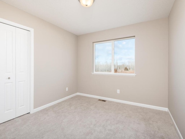 unfurnished bedroom featuring a closet and light colored carpet