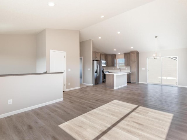 kitchen featuring appliances with stainless steel finishes, a center island, decorative light fixtures, and wood-type flooring