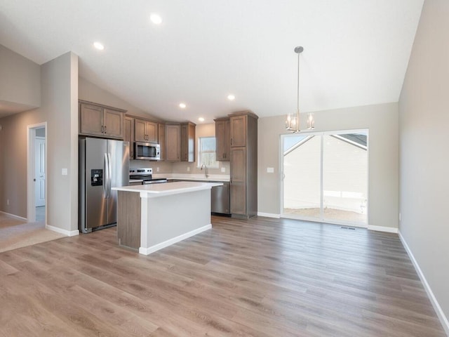 kitchen featuring appliances with stainless steel finishes, light hardwood / wood-style flooring, a kitchen island, and plenty of natural light