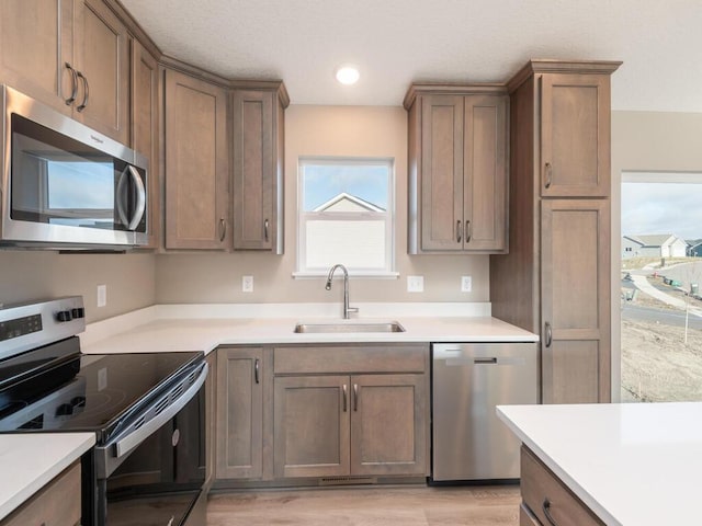 kitchen with sink, stainless steel appliances, and light wood-type flooring