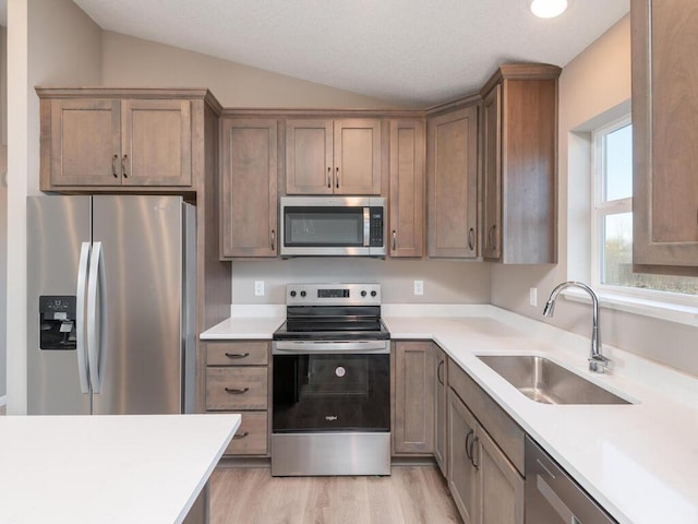 kitchen featuring sink, stainless steel appliances, lofted ceiling, and light hardwood / wood-style floors