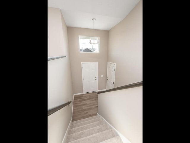 stairs with hardwood / wood-style flooring and a chandelier