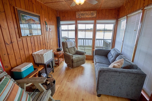 sunroom / solarium featuring ceiling fan and a water view