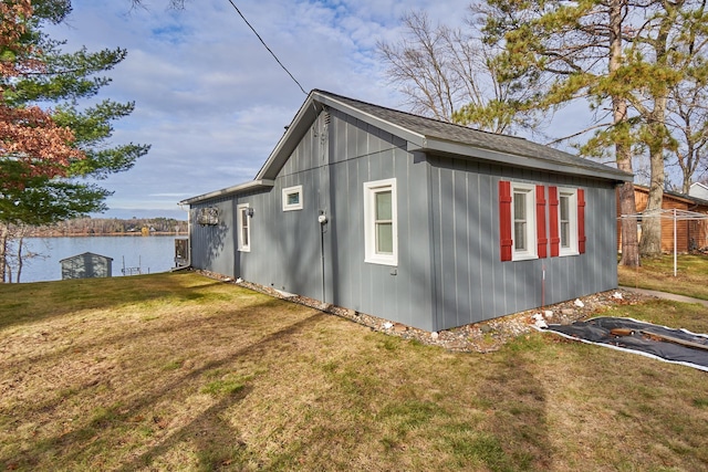 view of home's exterior with a lawn and a water view