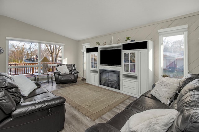 living room with hardwood / wood-style flooring, lofted ceiling, and wood walls