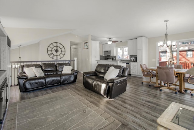 living room with an inviting chandelier, dark hardwood / wood-style flooring, and vaulted ceiling