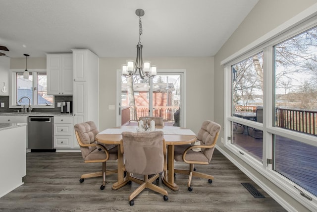 dining area featuring dark hardwood / wood-style flooring, sink, plenty of natural light, and an inviting chandelier