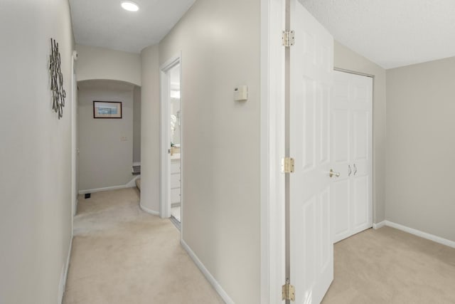 corridor with light colored carpet and a textured ceiling