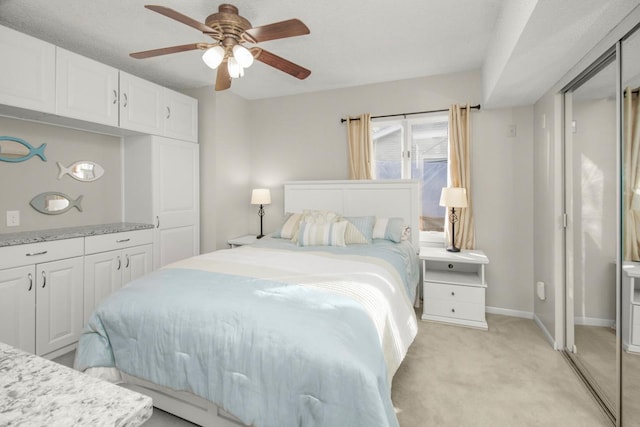 bedroom featuring light carpet, a textured ceiling, and ceiling fan